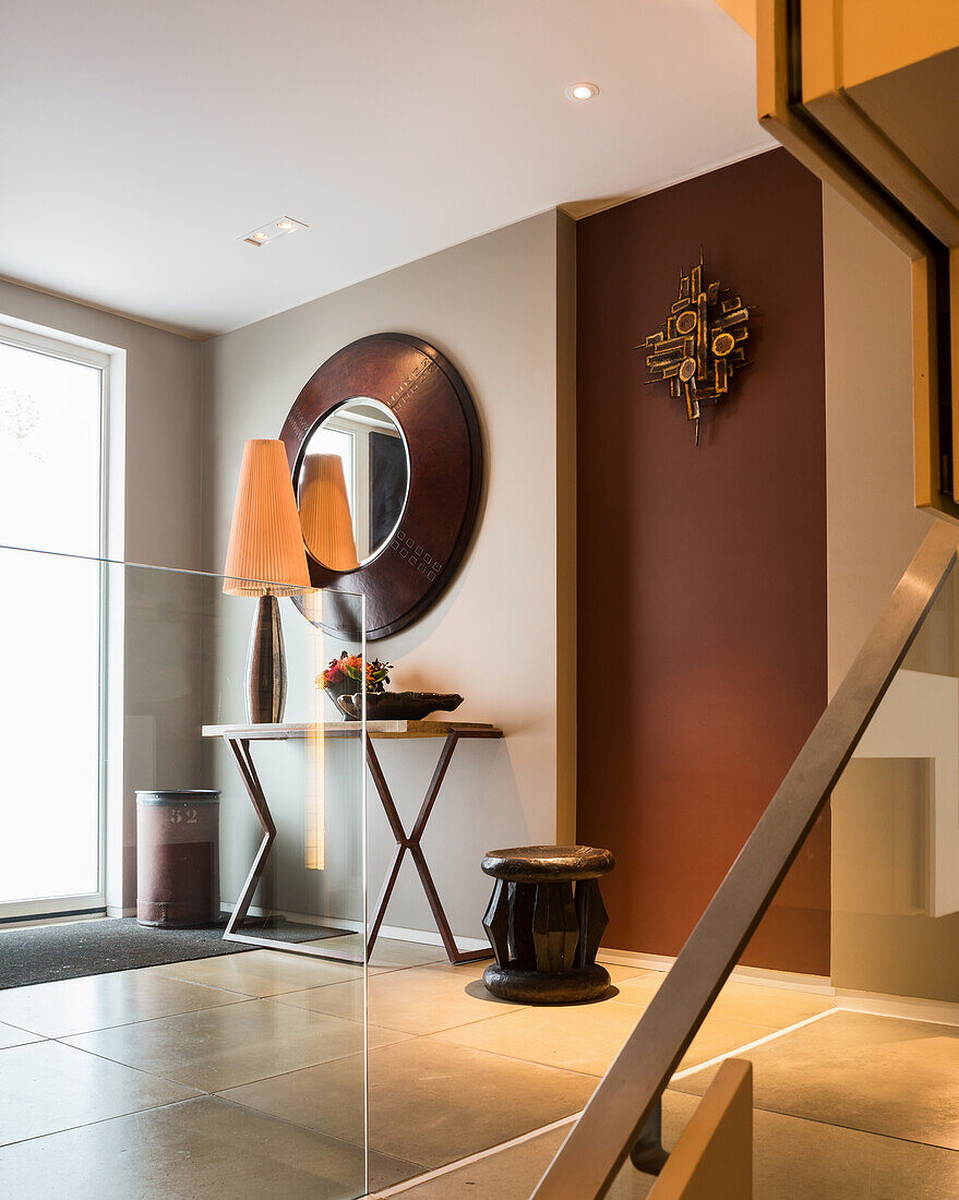 Large mirror above lamp on console table in hallway