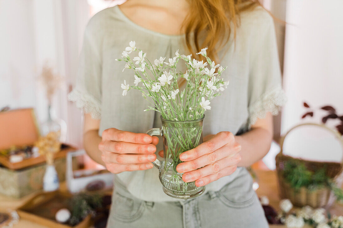 Young woman holding vase with fresh flowers