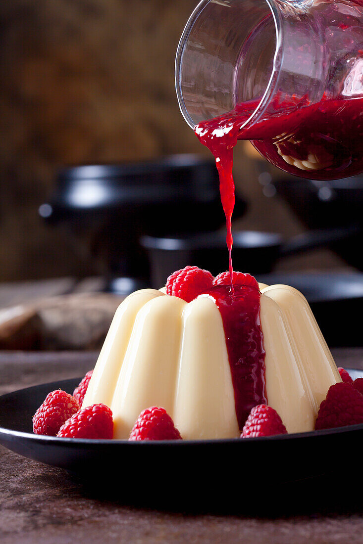 Pudding mit Himbeeren und Himbeersauce auf dem Teller