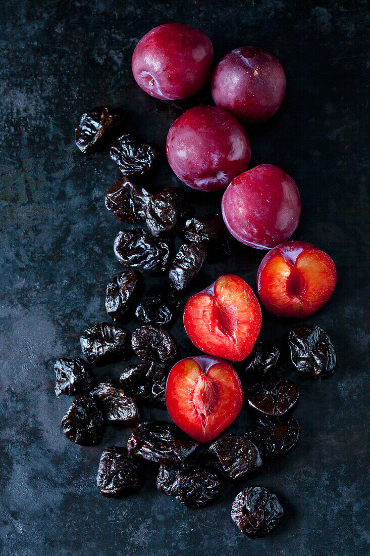 Fresh and dried plums on dark ground