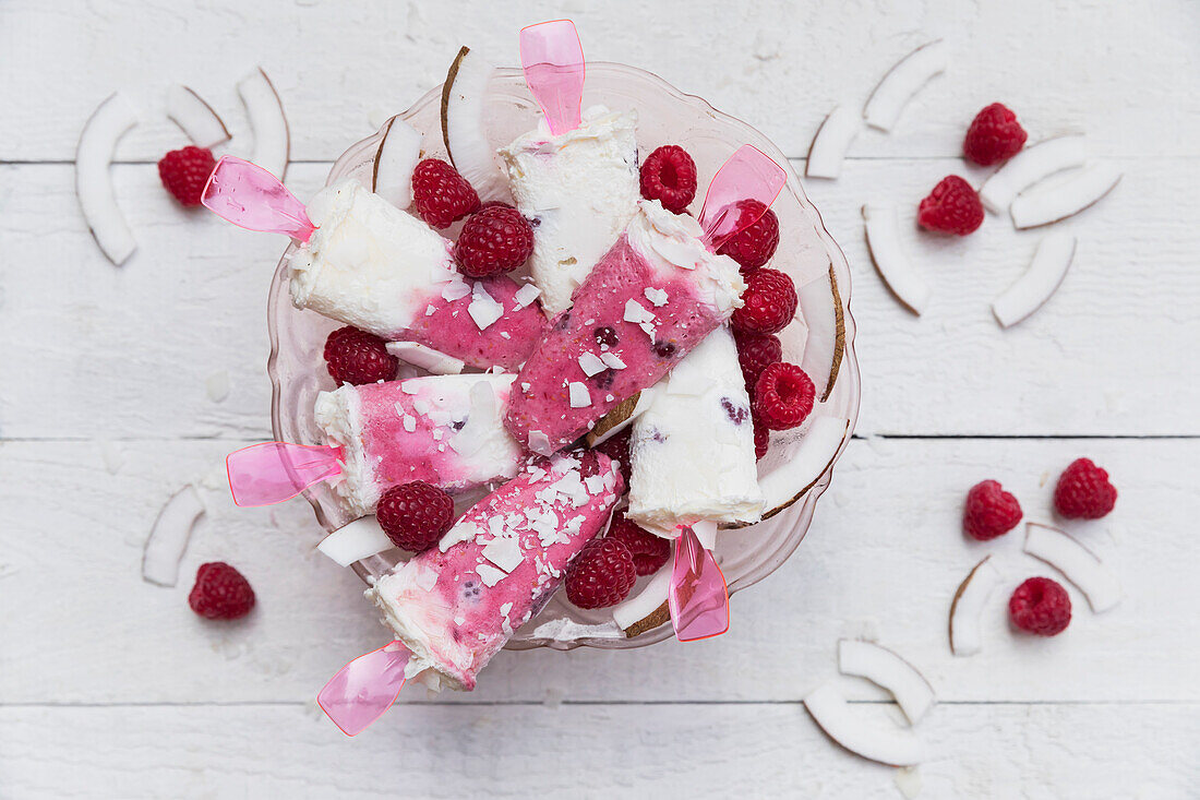 Homemade coconut and raspberry?popsicles in glass bowl