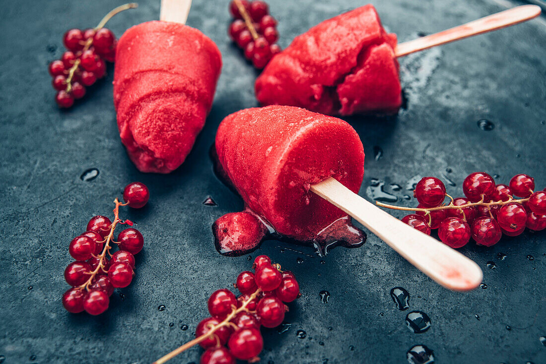 Homemade currant popsicles and red currants on slate