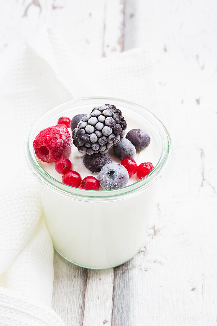 Glas griechischer Joghurt mit gefrorenen Beeren