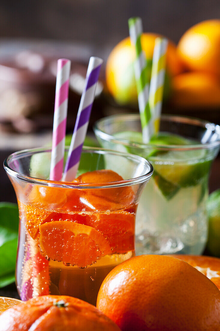 Fruchtschorle aus Mandarinen und Limetten im Glas mit Trinkhalmen