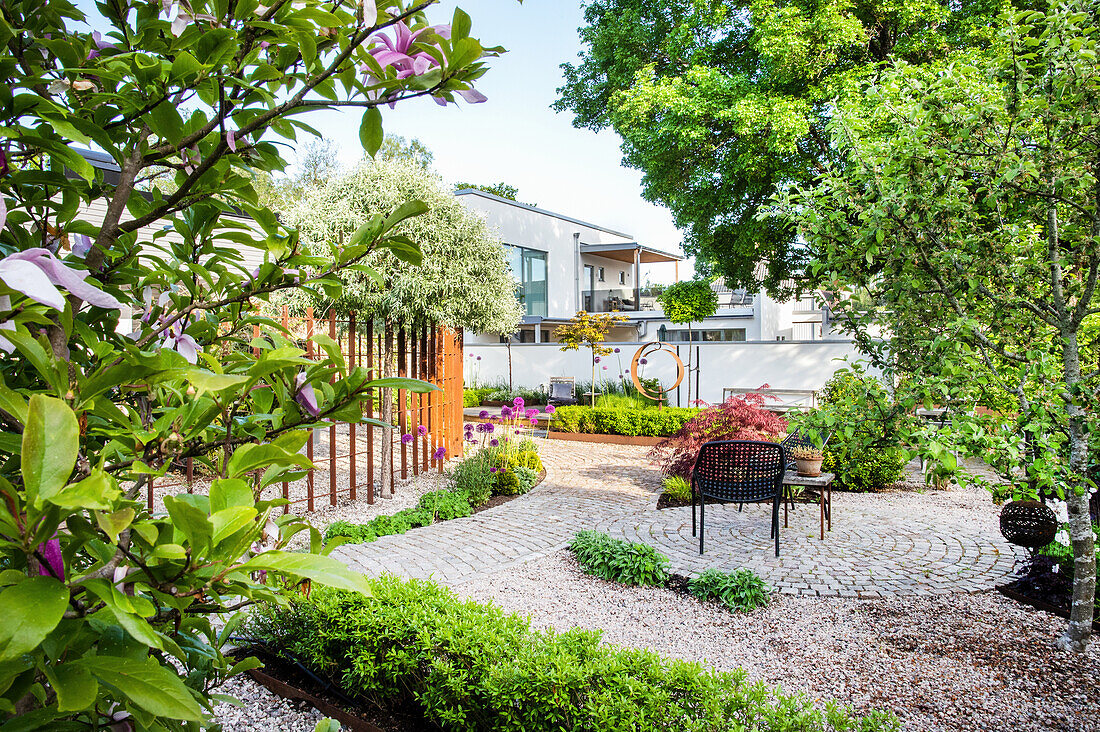 Seating area on paving stones in the garden with beds and gravel areas