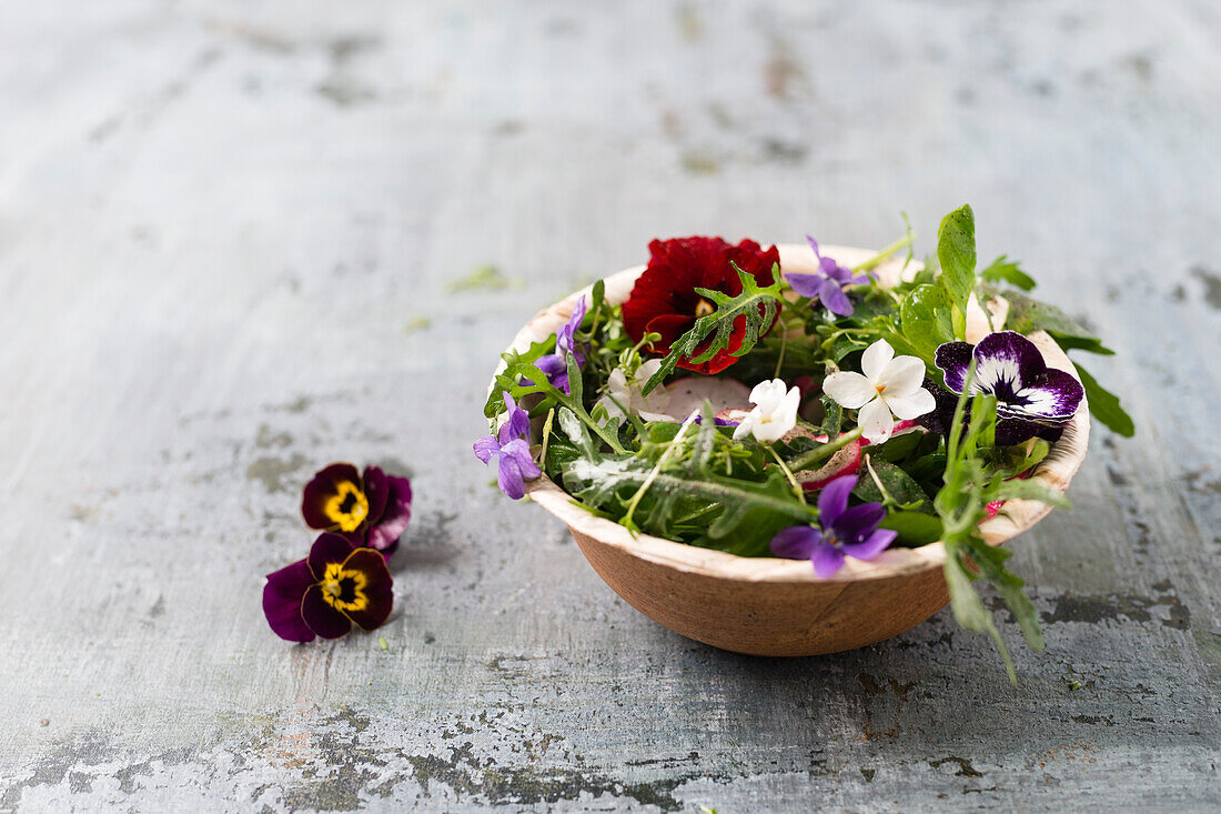 Bowl of leaf salad with red radishes, cress and edible flowers