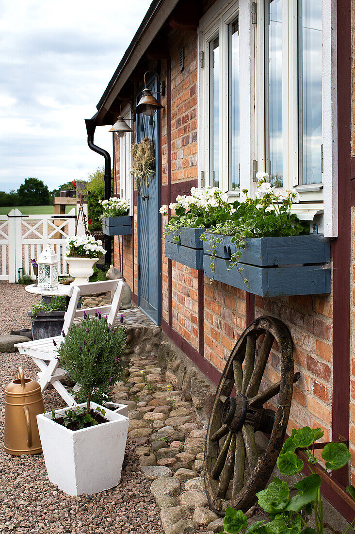 Blue-painted flower window boxes and an old wagon wheel on a brick façade