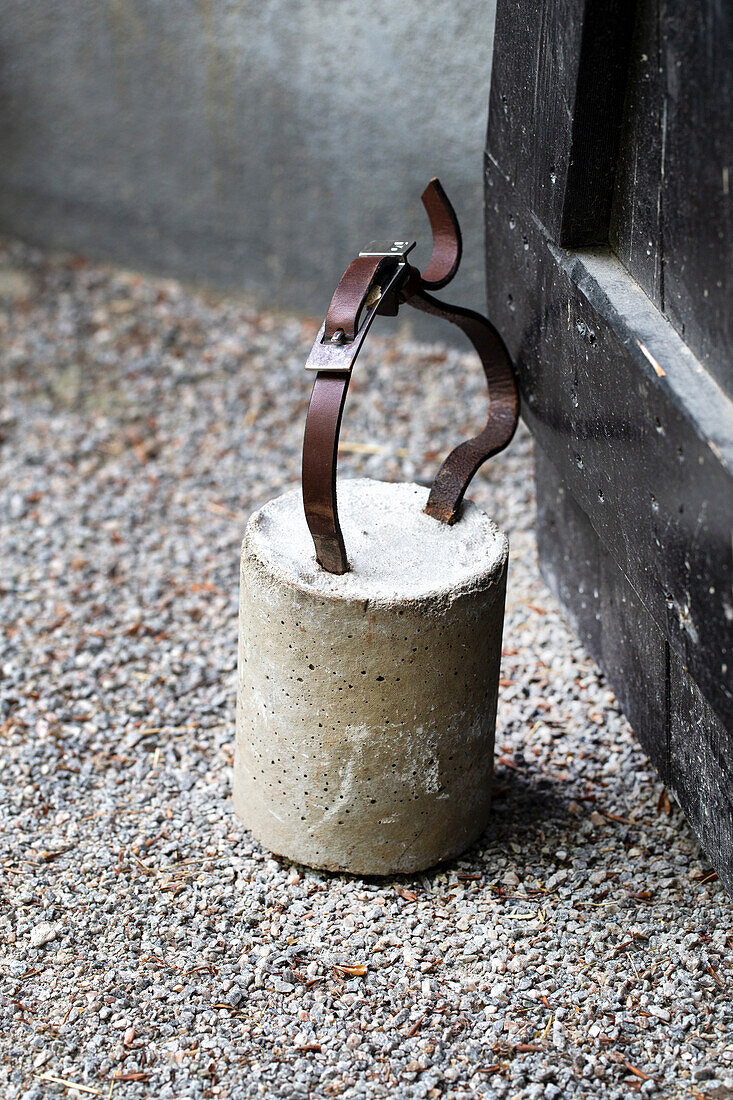 DIY doorstop made of concrete block and leather belt