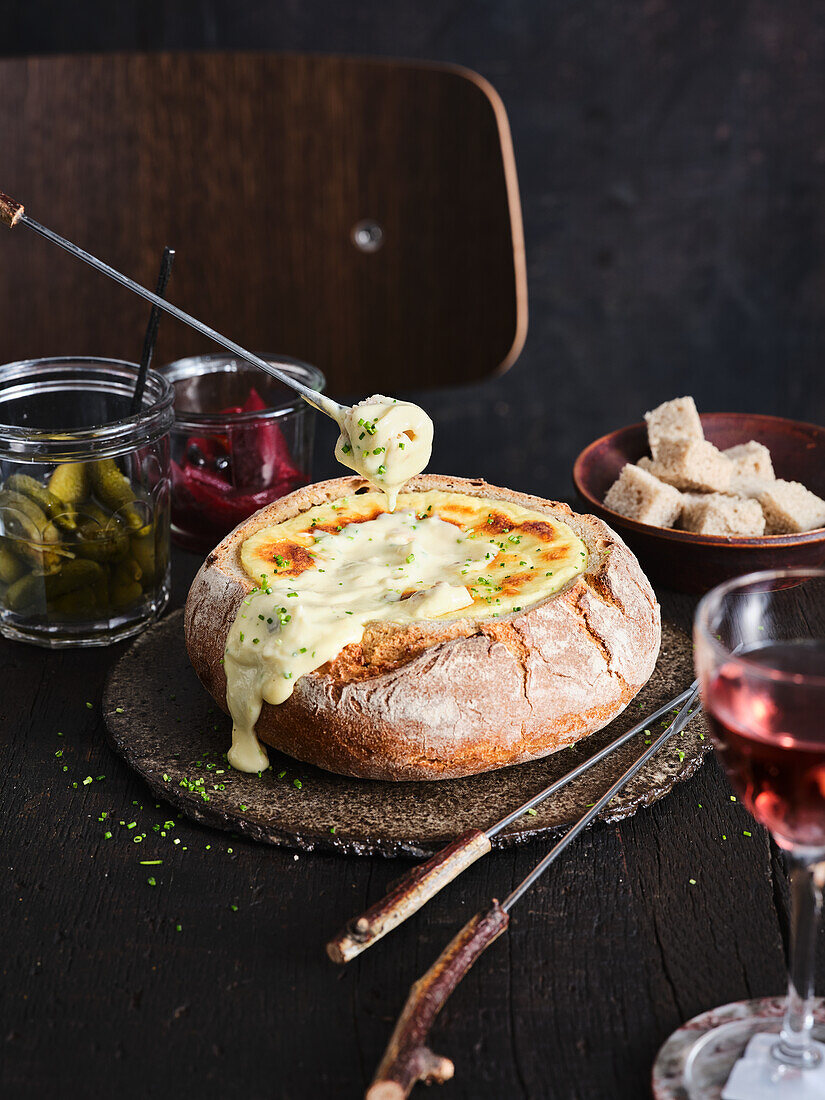 Cheese fondue in a bread loaf with mixed pickles