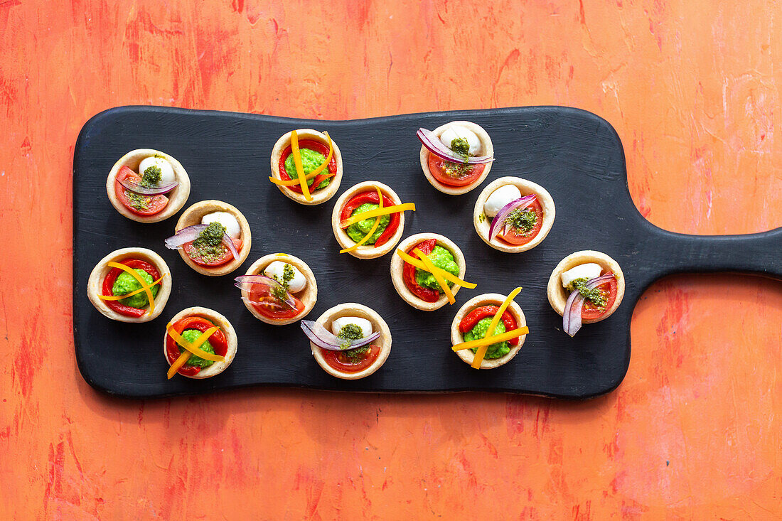 Tartelettes mit Mozzarella, Erbsenpüree, Paprika, Pesto, roten Zwiebeln und Tomaten