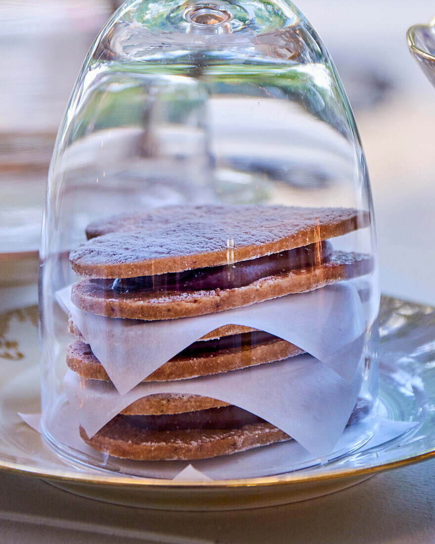 Filled shortbread hearts with chocolate cream under a glass cover