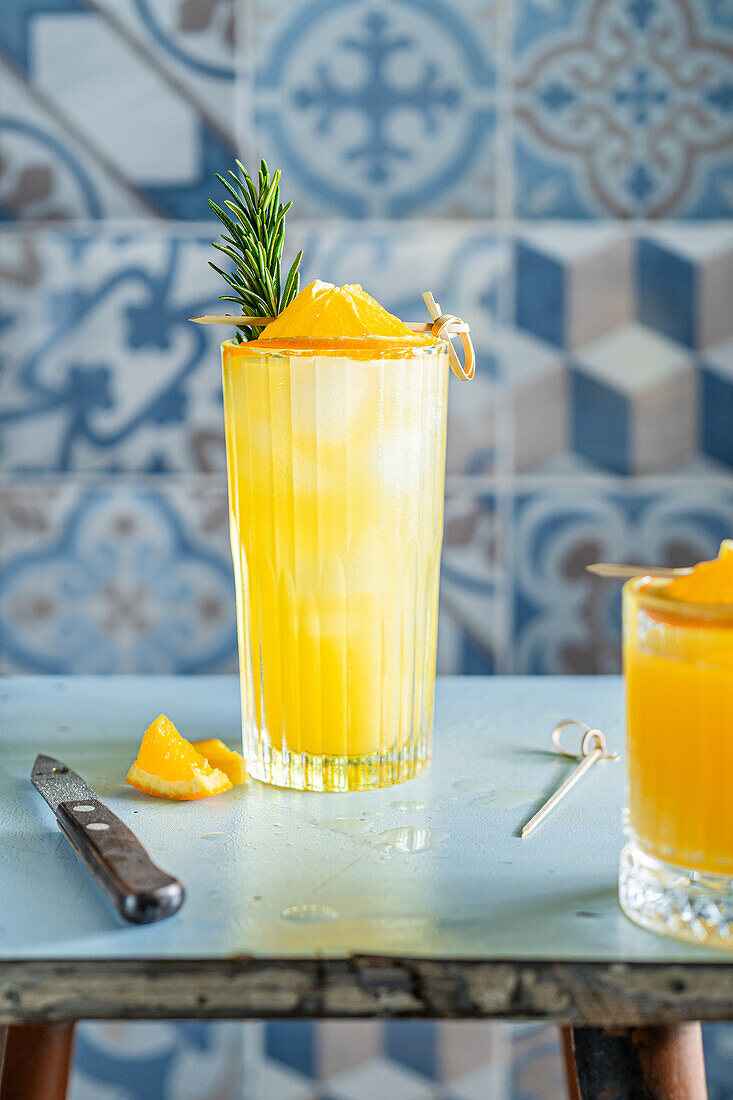 Orangencocktail mit Rosmarin und Eiswürfeln