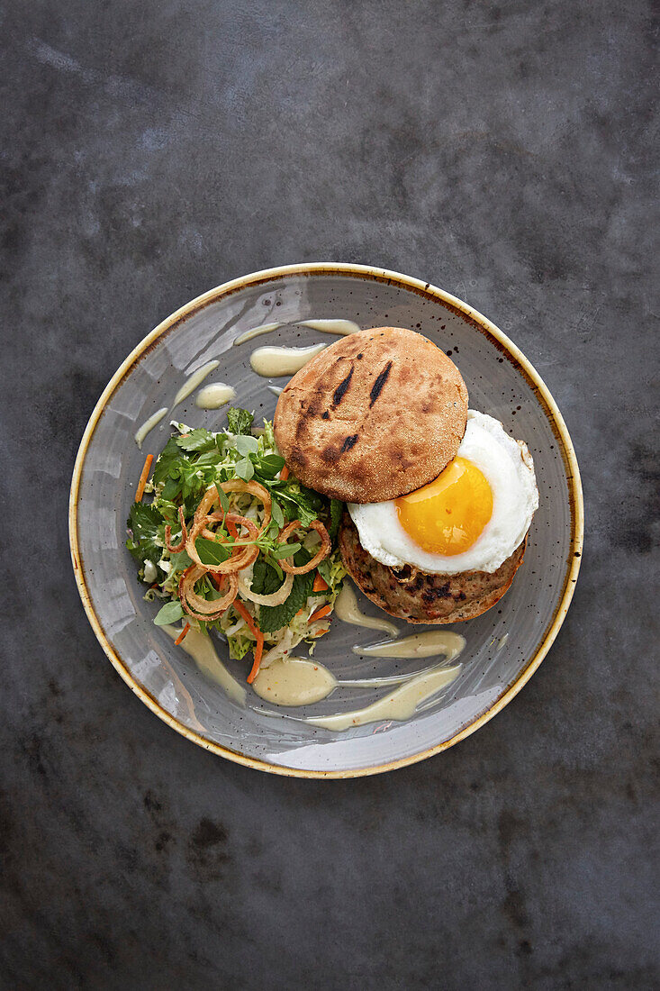 A burger with fried egg and side salad