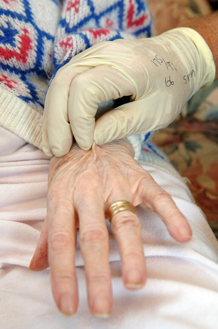 Paramedic checking dehydration of elderly patient