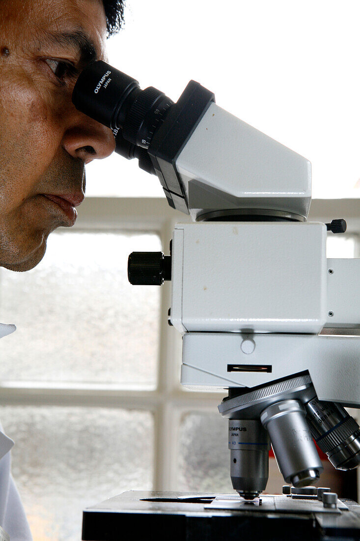 Pathologist analysing a sample under a microscope