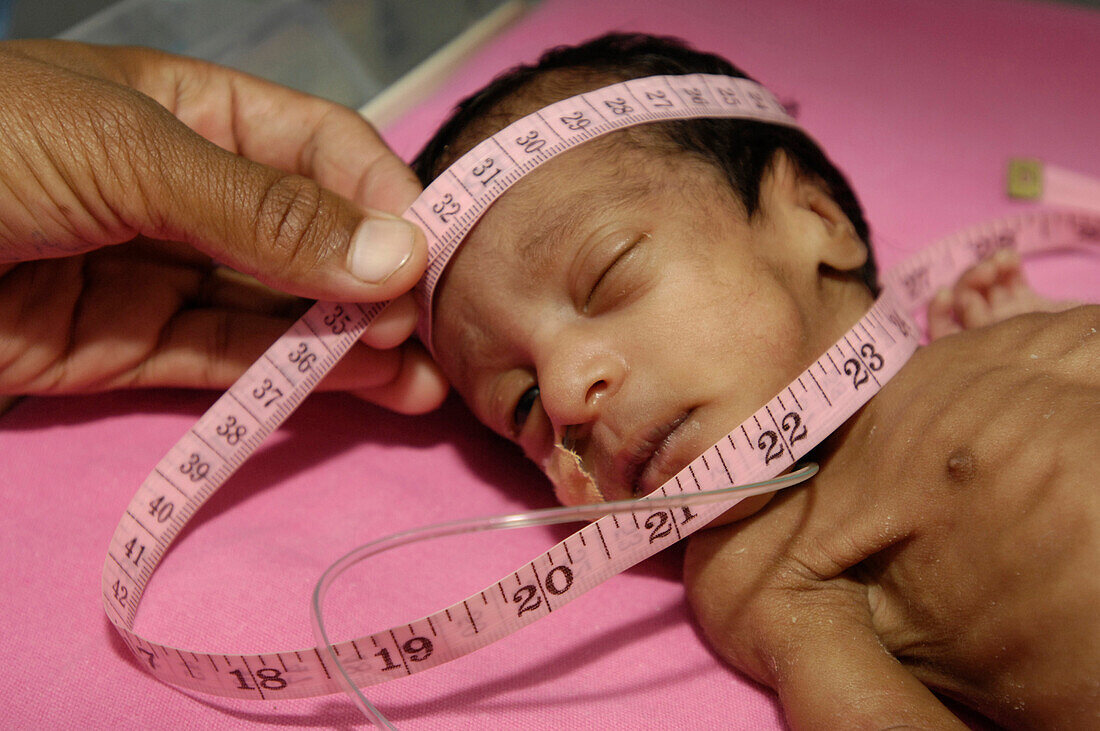 Neonatal nurse measuring the head of a premature baby