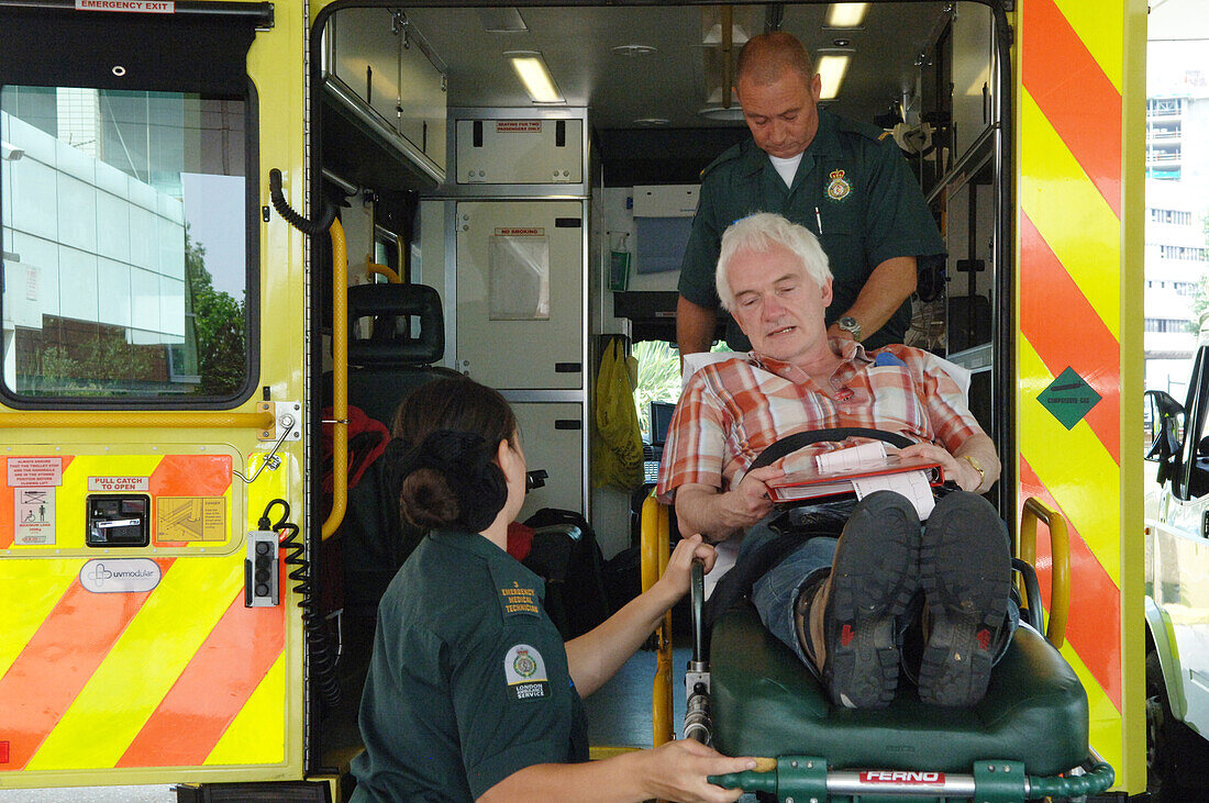 Paramedic loading an elderly patient onto an ambulance.