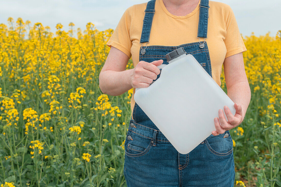 Farming holding herbicide in rapeseed field