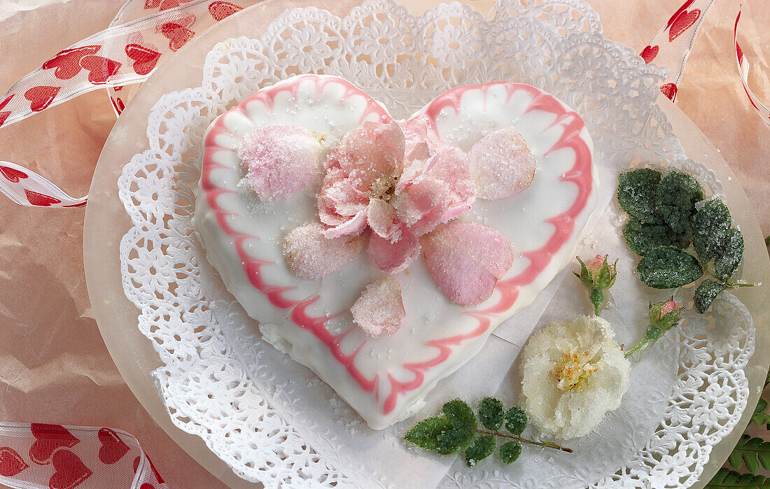 Herzförmige Torte zum Valentinstag, mit gezuckerten Rosenblüten