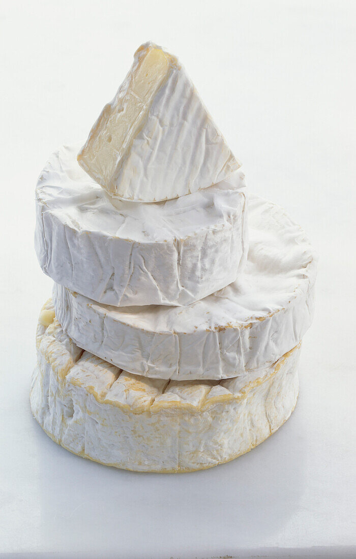 Stack of Camembert wheels with a wedge of Camembert on the top
