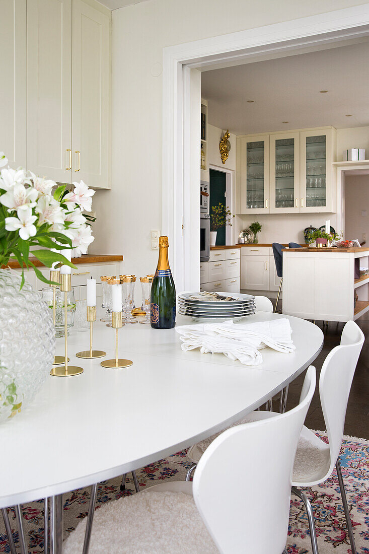 White oval table with flowers, candles and champagne in dining area