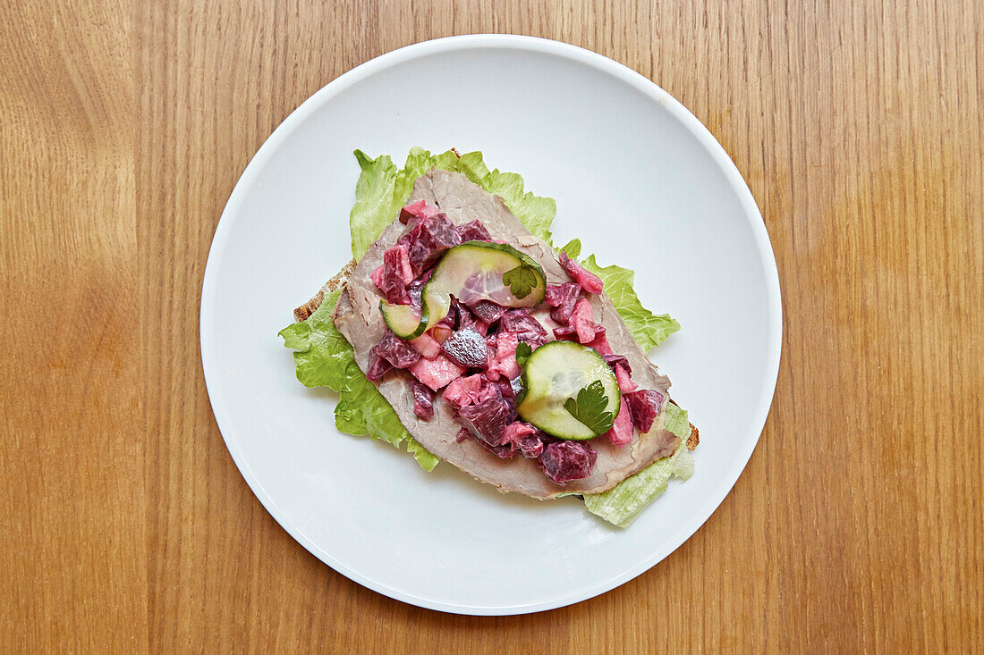 A open sandwich of beef, beetroot and salad on rye bread