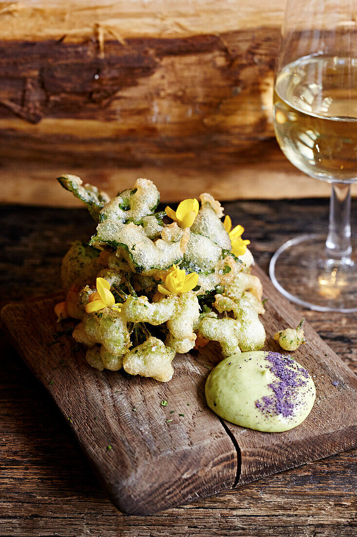 Tempura serviert auf Holzbrett mit Dip und einem Glas Weißwein