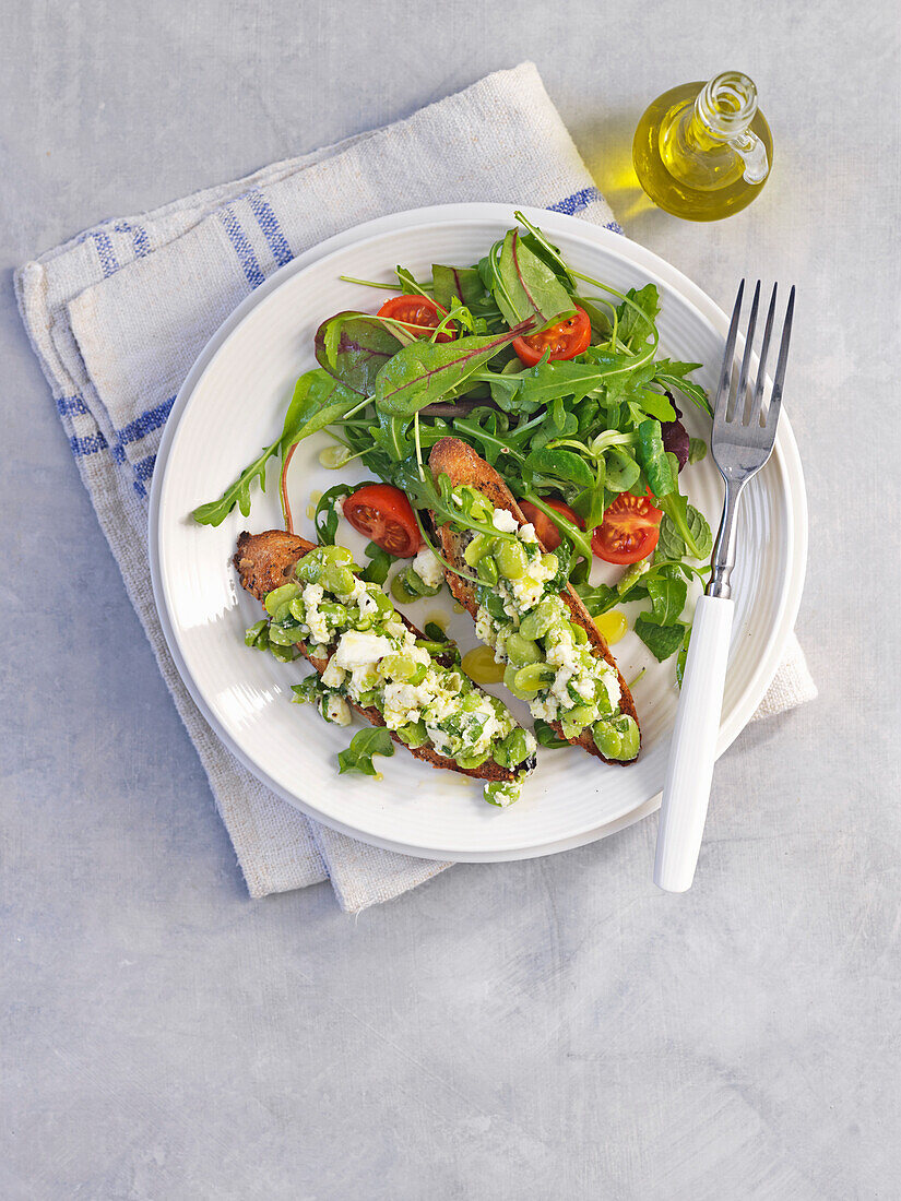 Röstbrot mit Ackerbohnen und Feta dazu Blattsalat