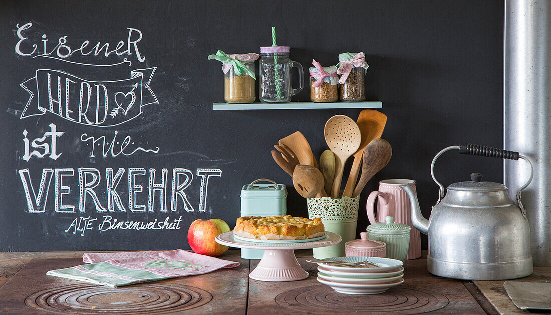 Wall with chalkboard paint and worktop with cake, kettle and crockery