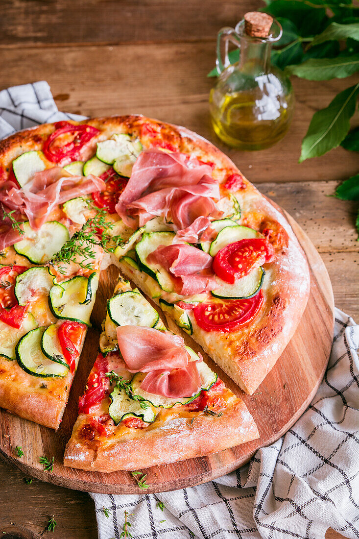 Hausgemachte Pizza mit Zucchini, Tomaten und Parmaschinken