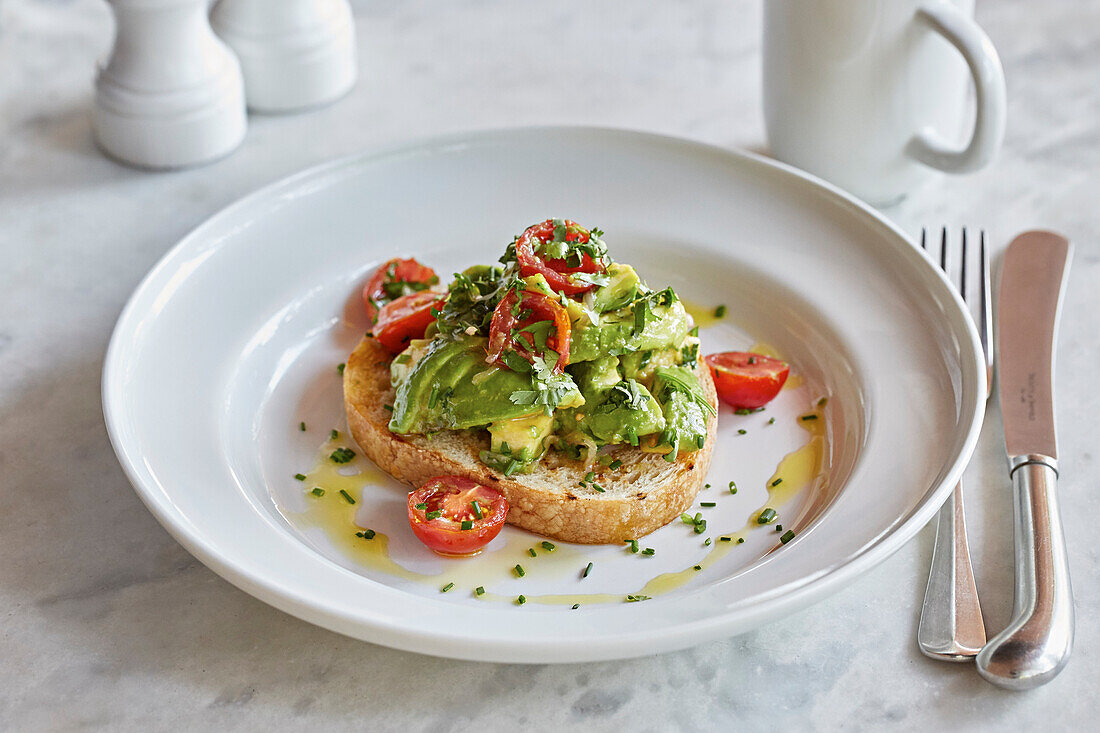 Brotscheibe mit Avocado, Tomaten und Petersilie