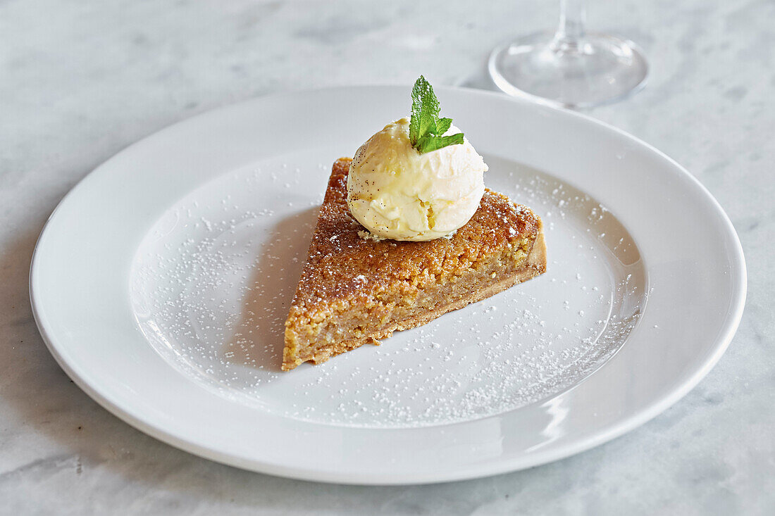 Ein Stück Mandelkuchen mit einer Kugel Vanilleeis