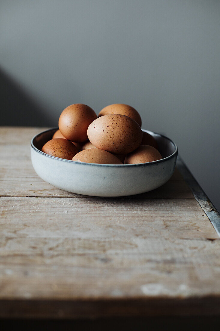 Fresh eggs in a bowl on a wooden table