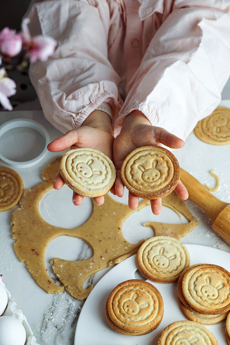 Mädchenhände halten Plätzchen mit Osterhasenmotiv