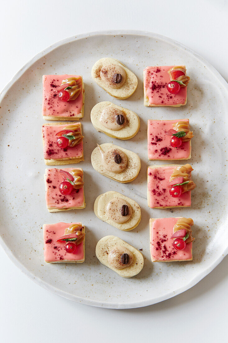 Small petit fours of puff pastry with mocha cream and raspberry glaze