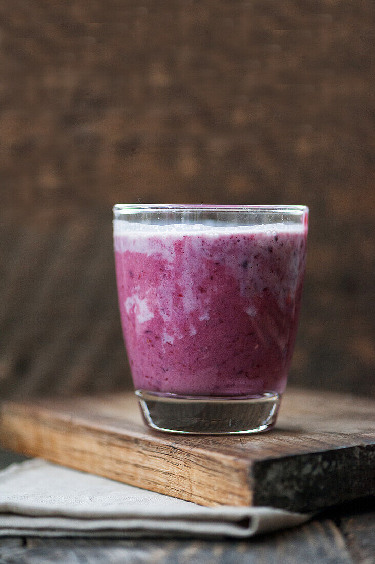 Blueberry smoothie in a glass on a wooden plank