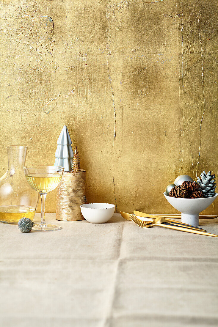 Christmas decoration and white wine in a glass and carafe against a golden background
