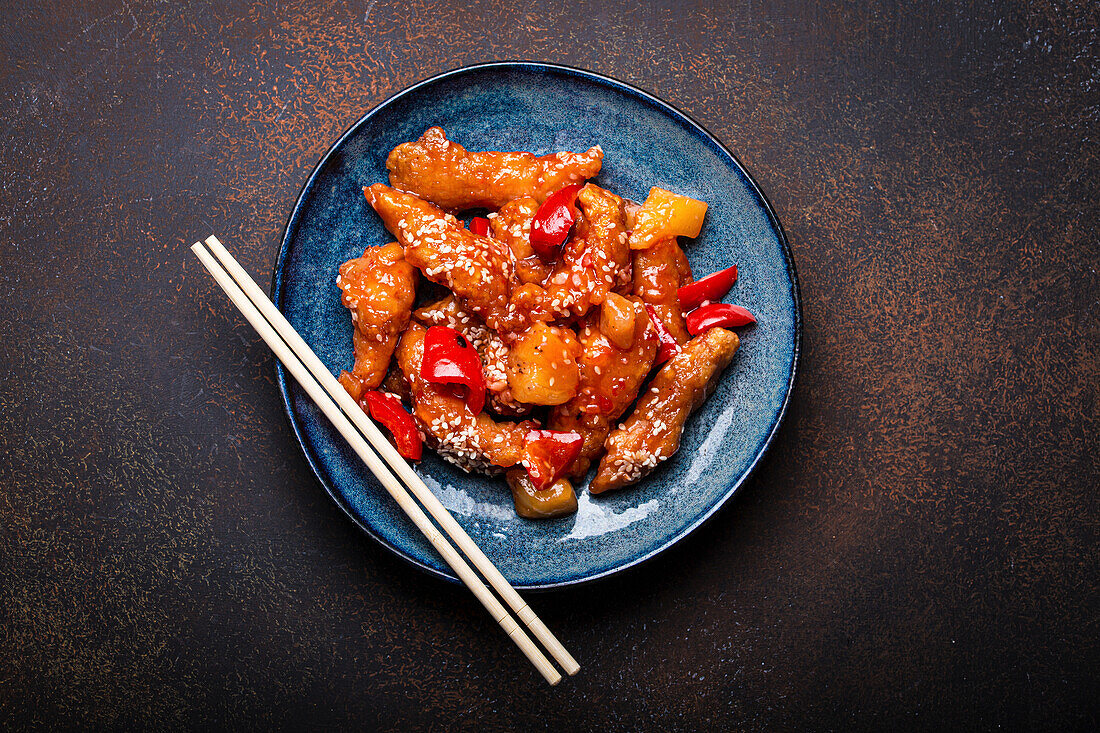 Chinese traditional wok dish sweet and sour deep fried chicken with vegetables stir-fry on plate with sesame seeds