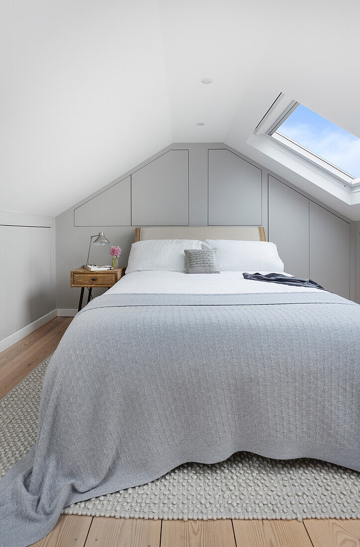 Double bed with grey bedspread in attic bedroom