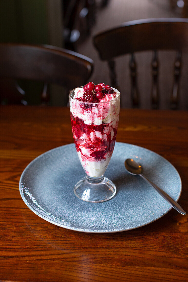 A layered dessert with ice cream, raspberries, redcurrants and cream