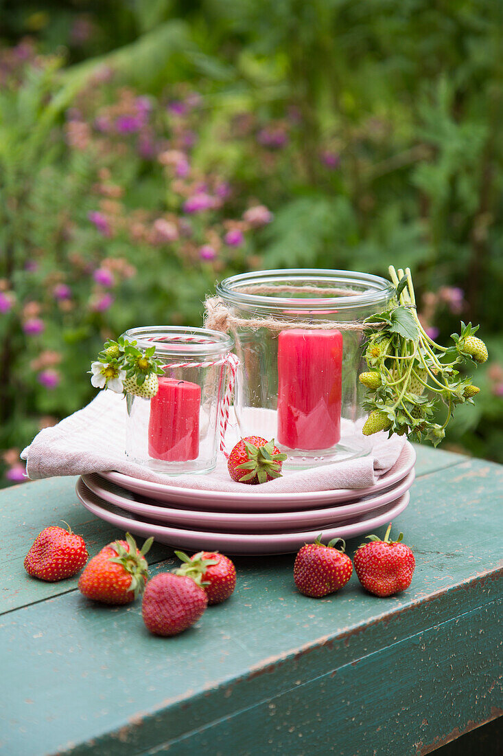 Tellerstapel, Windlichter und frische Erdbeeren auf Gatentisch