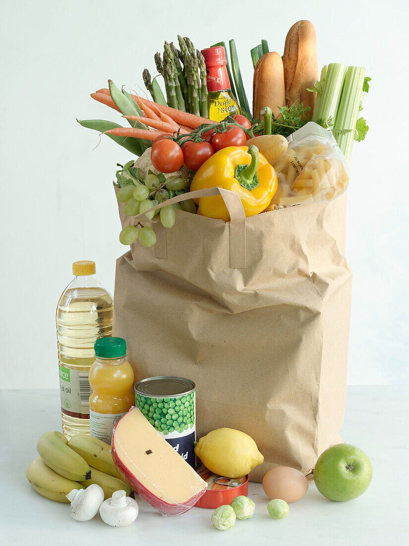 Paper bag with groceries - vegetables, fruit, pasta, cheese, oil, and juice