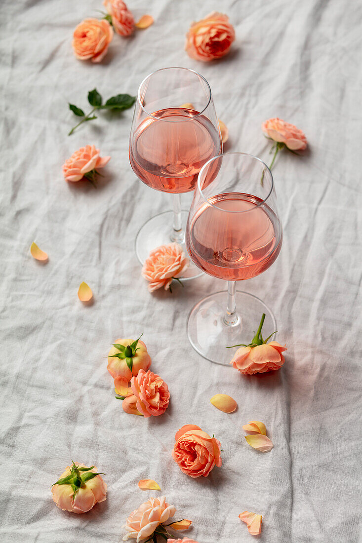 Roséwein in Gläsern drumherum Rosenblüten