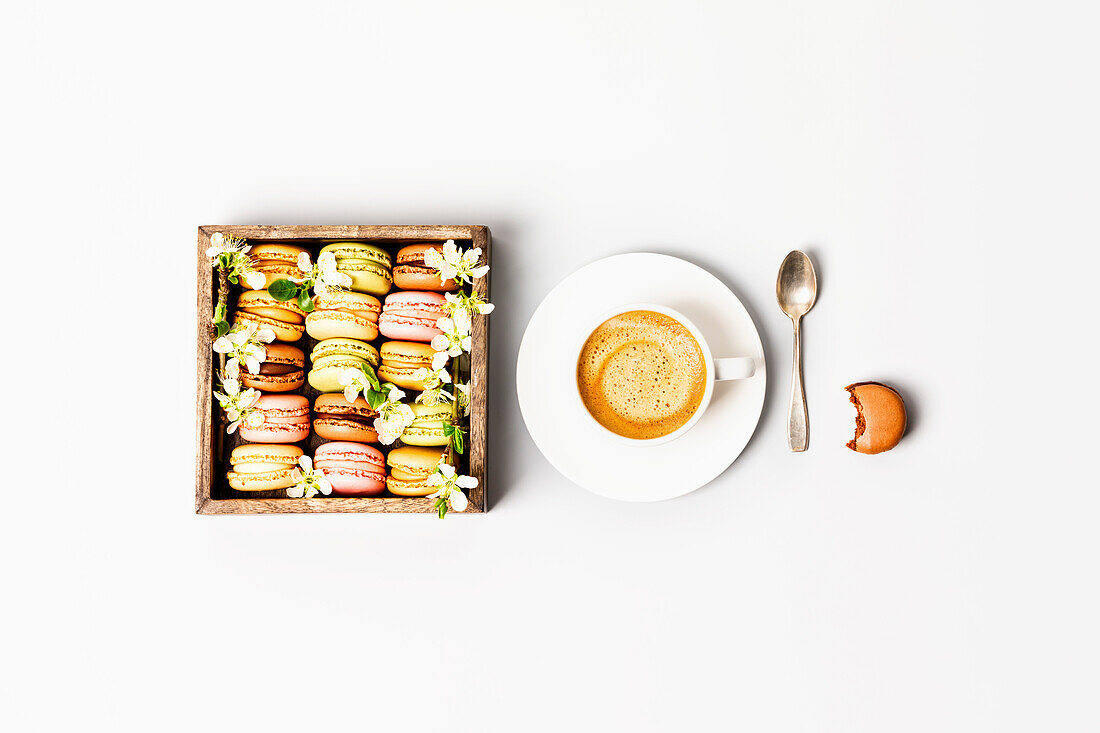 Macaroons in wooden box with spring flowers and cup of coffee