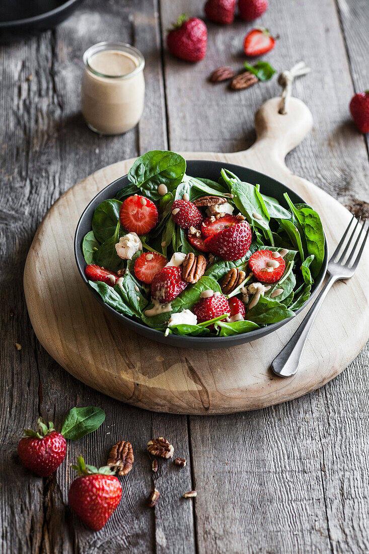 Spinatsalat mit Erdbeeren und Pekannüssen auf rustikalem Holztisch