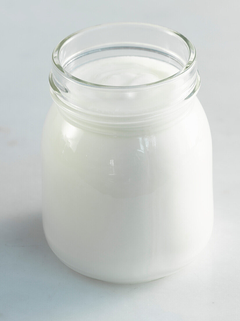Ein Glas Joghurt auf hellem Untergrund