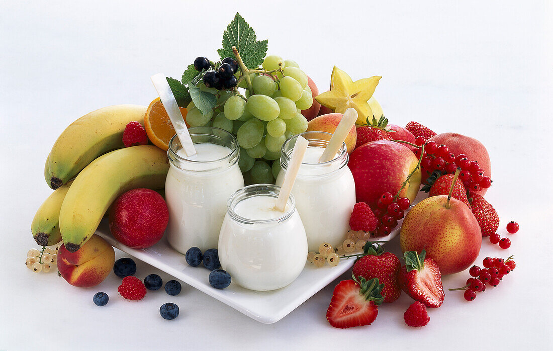 Drei Gläser Joghurt, umgeben von Obst