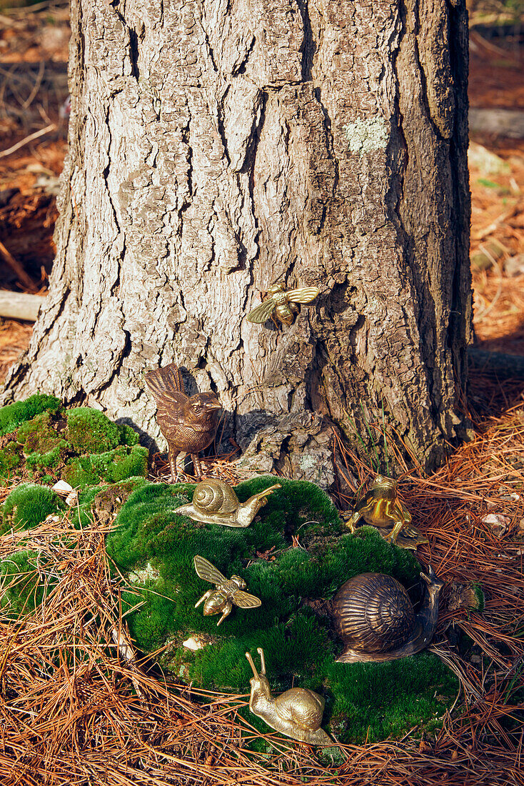 Decorative bird and snails on moss on forest floor