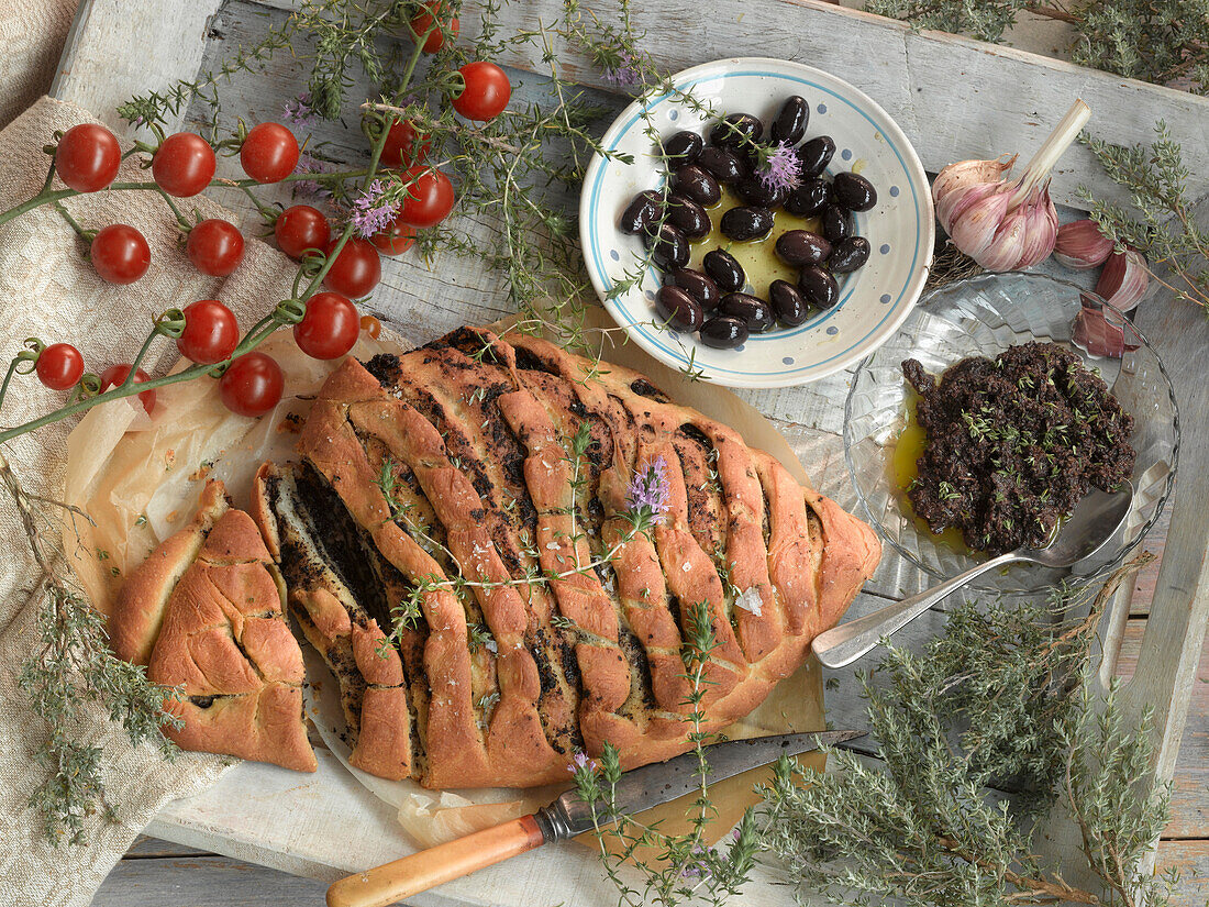 Still life with olive bread, olive pesto, olives, tomatoes, and thyme