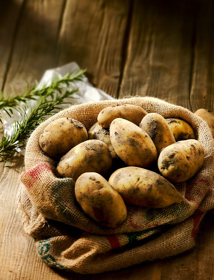 Kartoffeln im Jutesack dahinter Rosmarin